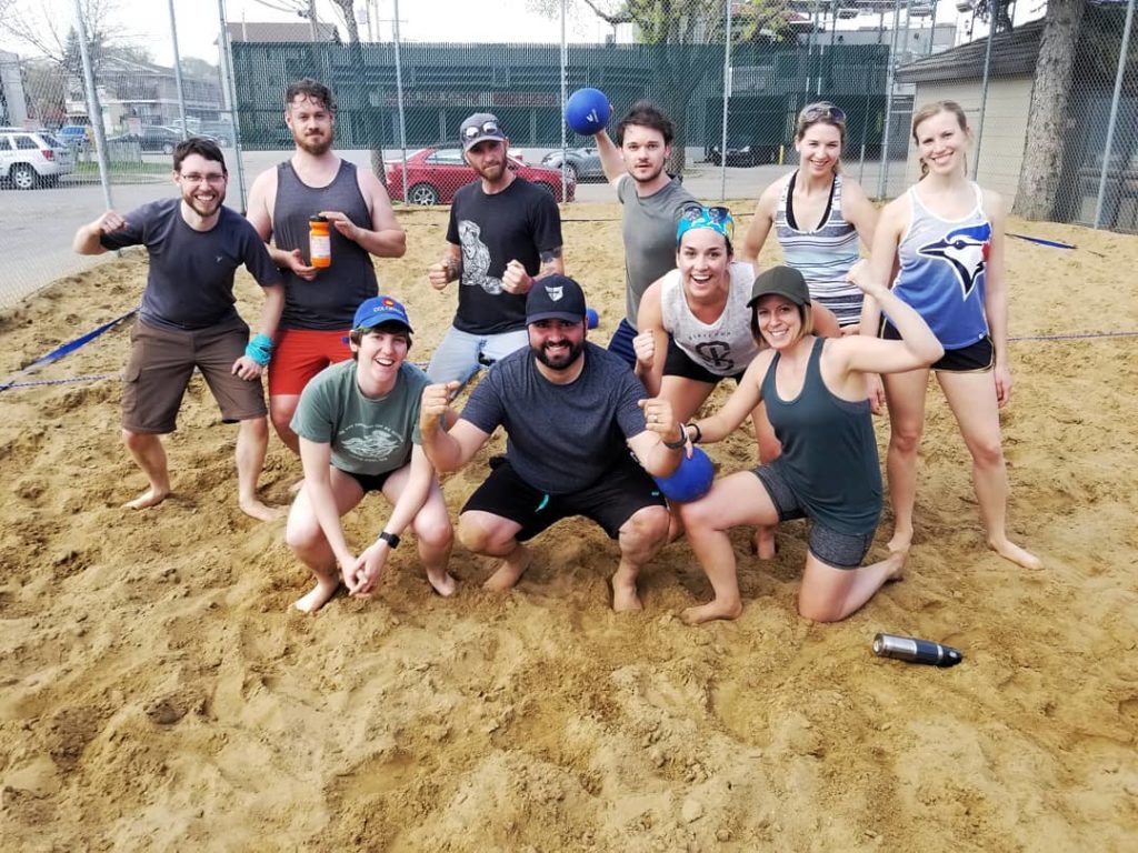 A team celebrating on a beach dodgeball court.