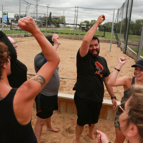 A beach dodgeball team cheering at the end of a game.