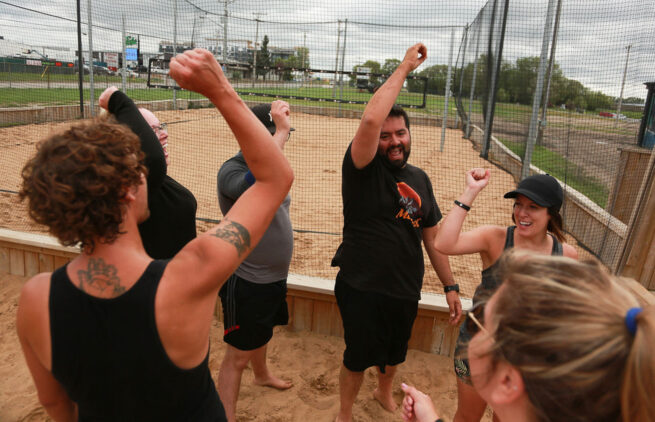 A beach dodgeball team cheering at the end of a game.