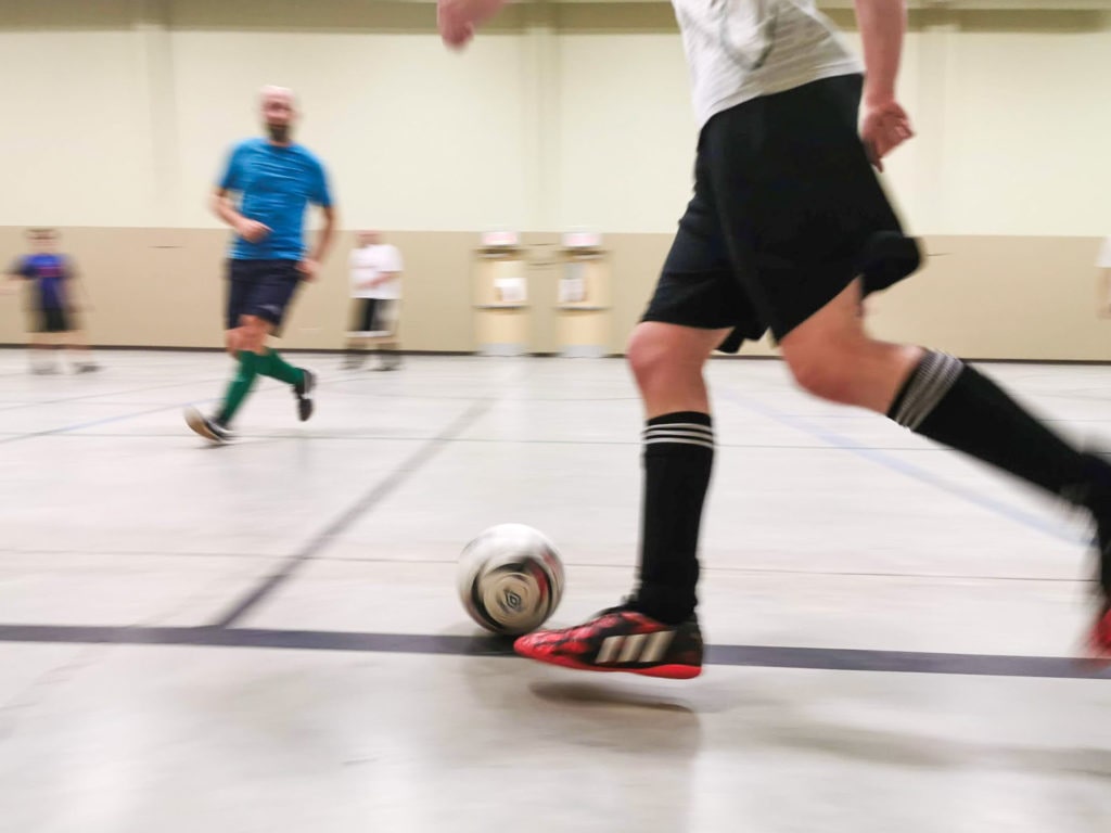 Someone dribbling a ball in indoor soccer.