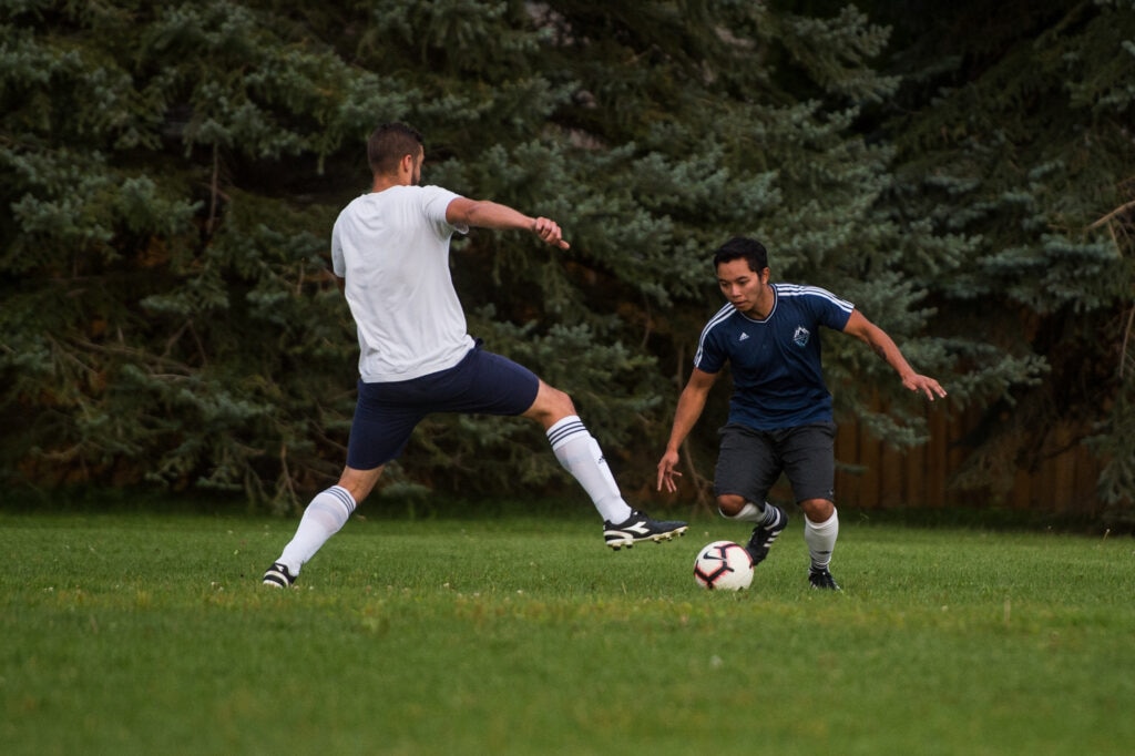 Two men playing soccer in a park.
